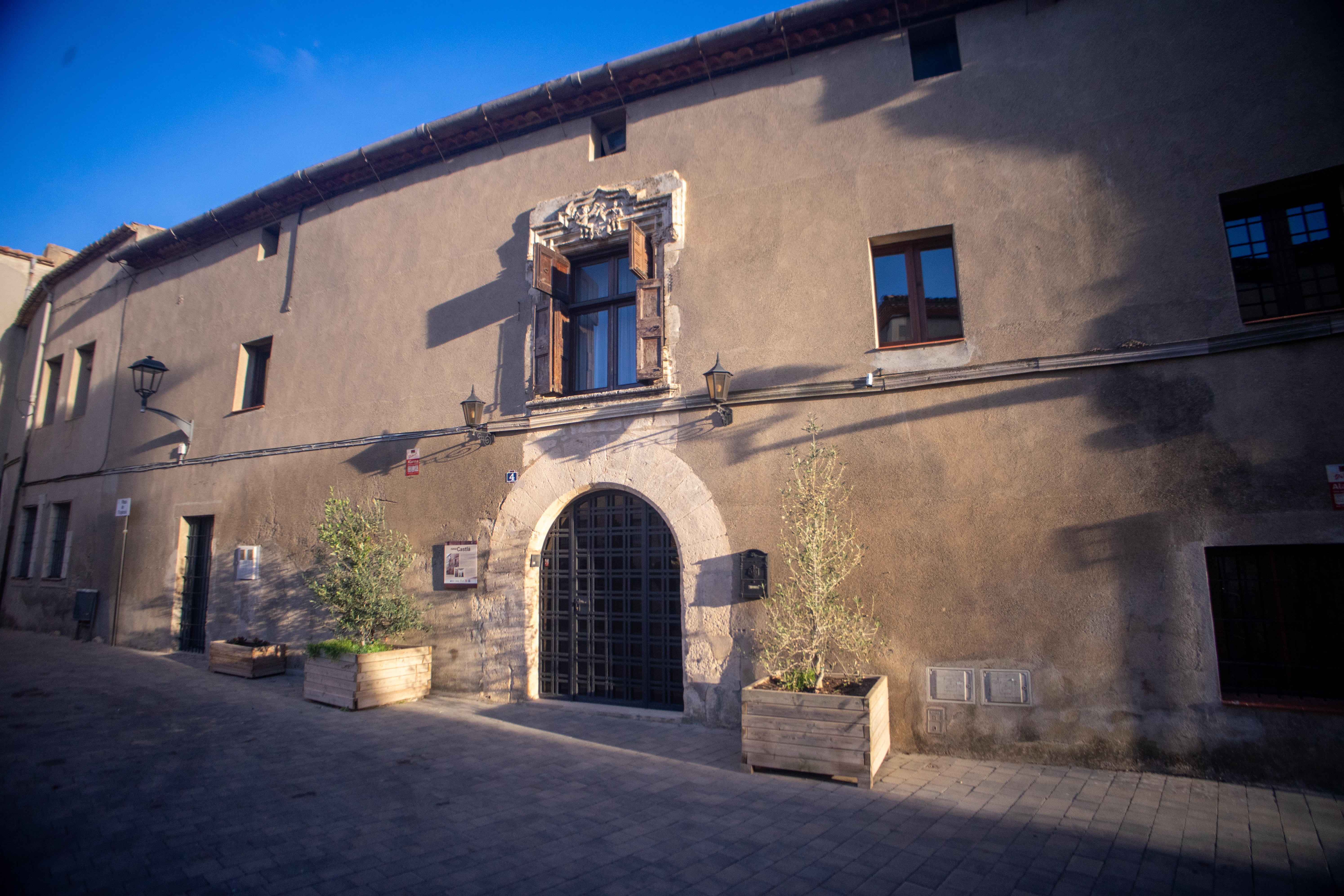 Fachada histórica de Can Castellà con portal en arco de piedra y ventana balconera